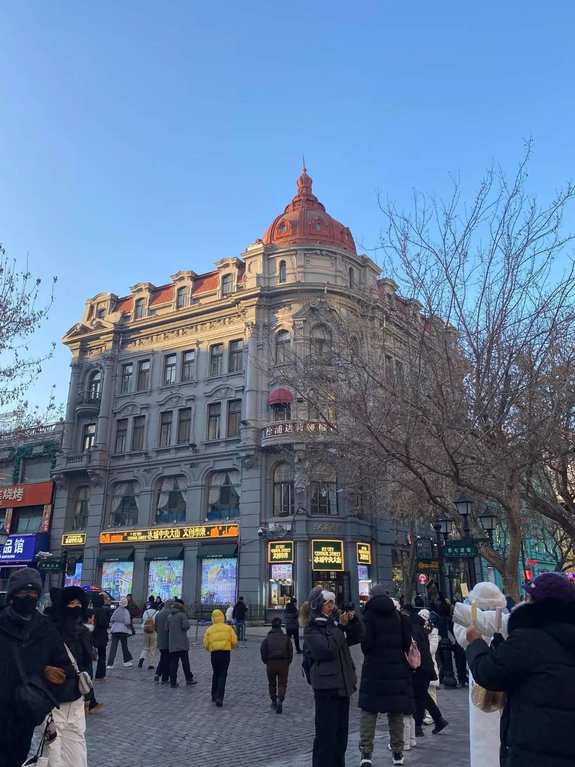 A domed corner building on a busy pedestrian street on a clear winter day