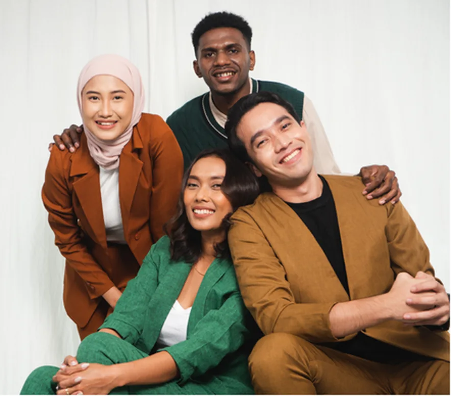Four colleagues standing together in front of a plain backdrop